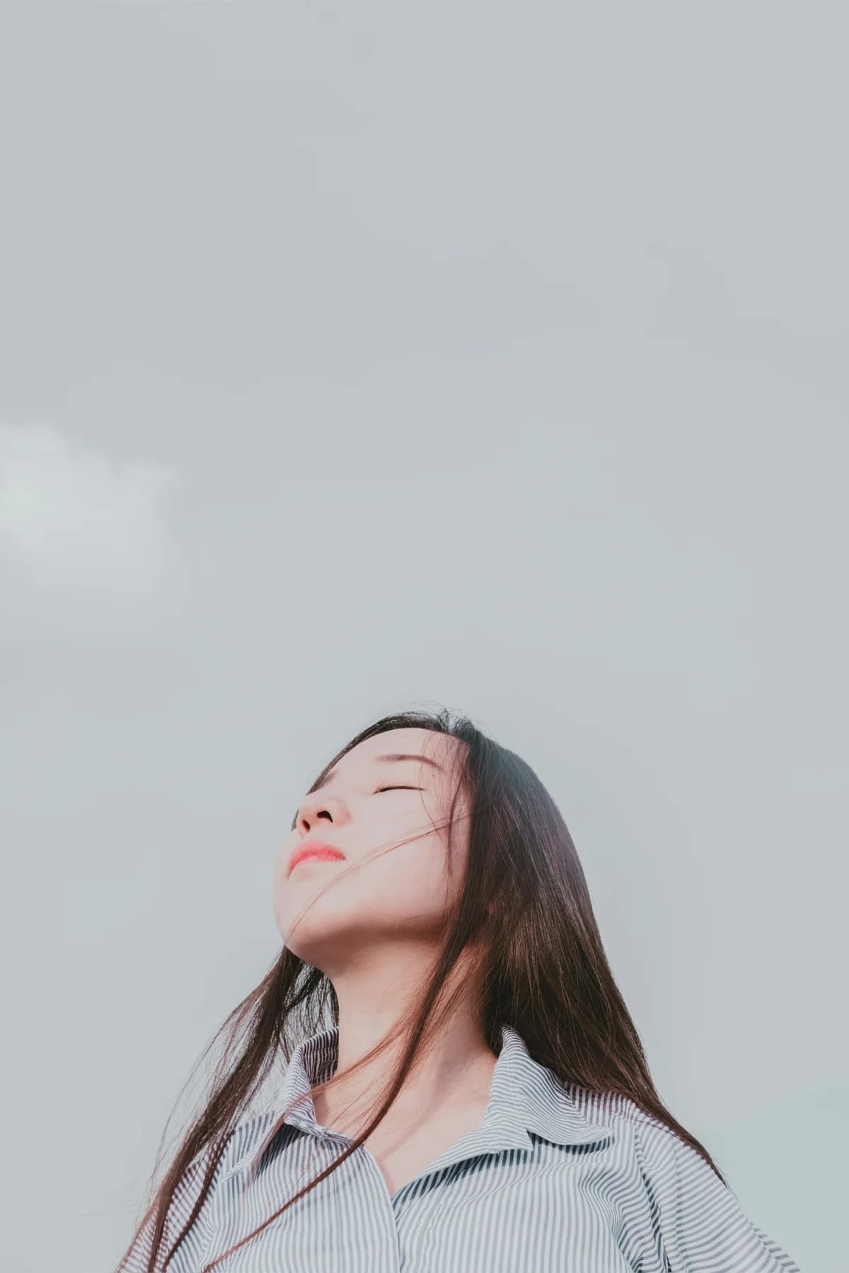 A person with eyes closed and face tilted towards the open sky