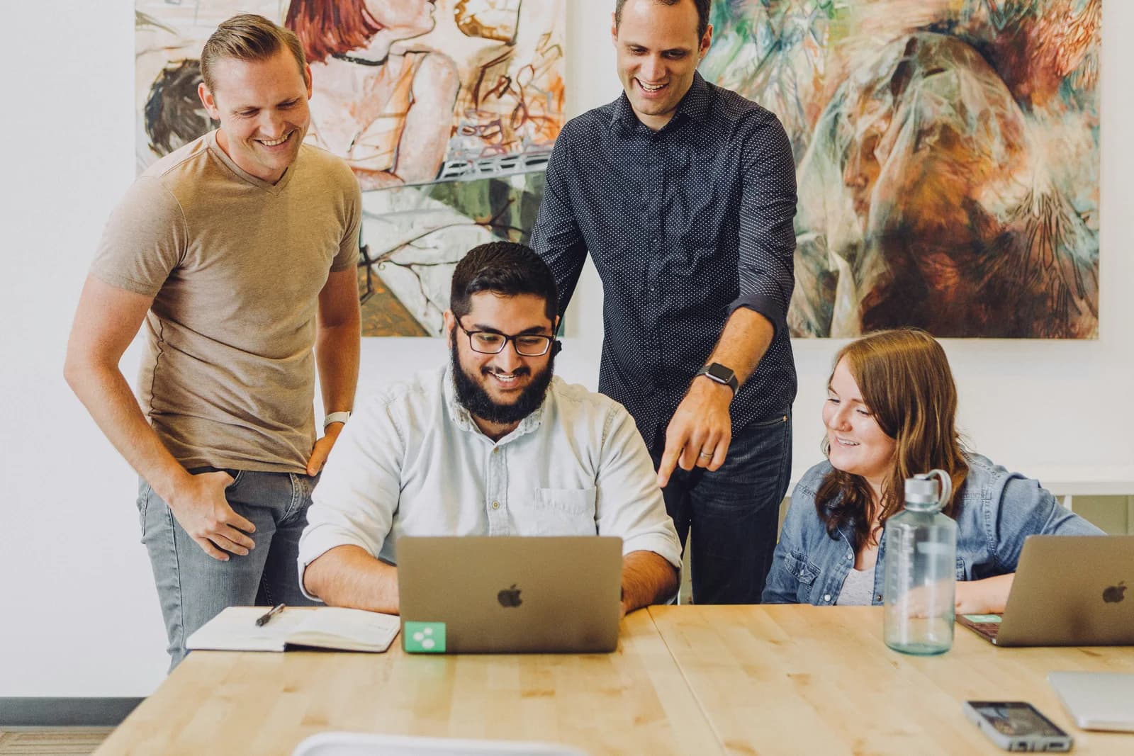 Colleagues gathered around a laptop in a creative workspace